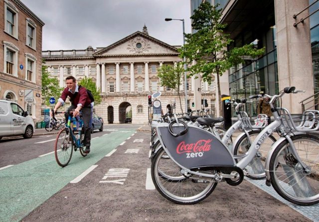 A cyclist making use of one of Belfast City Centre’s cycle lanes passes one of the Belfast Bikes scheme docking stations 