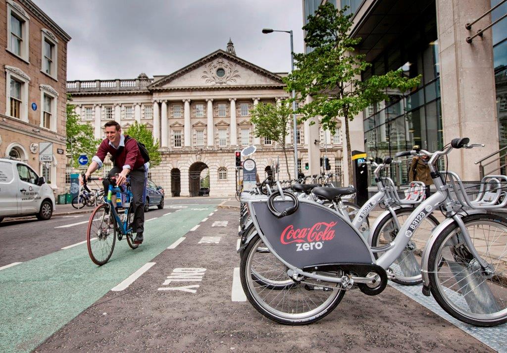 A cyclist making use of one of Belfast City Centre’s cycle lanes passes one of the Belfast Bikes scheme docking stations