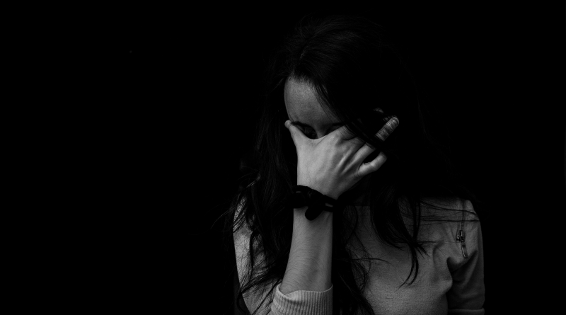 A black and white image of a woman with her hand covering her face