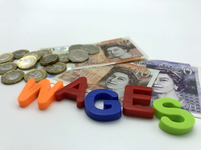 Image showing the word 'wages' spelled out with some cash behind.