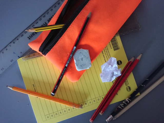 A picture showing some scruffy stationery items on a school desk