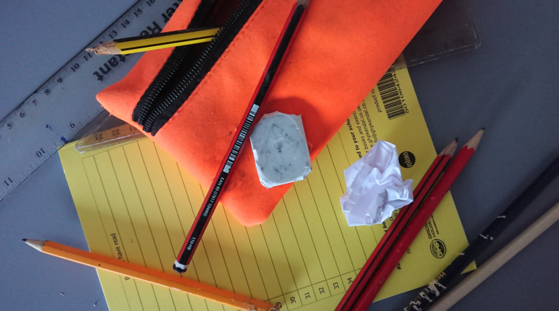 A picture showing some scruffy stationery items on a school desk