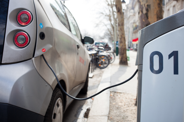 An image showing an electric car charging in the street