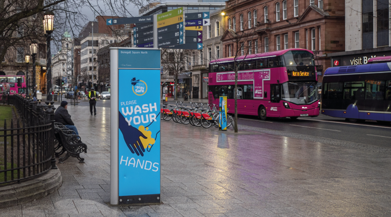 An image of the centre of Belfast with buses whizzing past COVID-19 signs