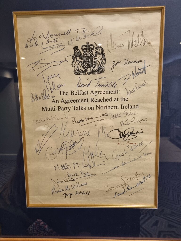 A photograph of the front page of the Belfast/Good Friday Agreement, signed by each of the parties