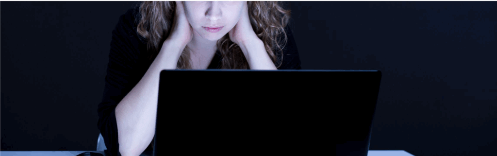 An image showing a woman using a laptop screen and looking worried or anxious.