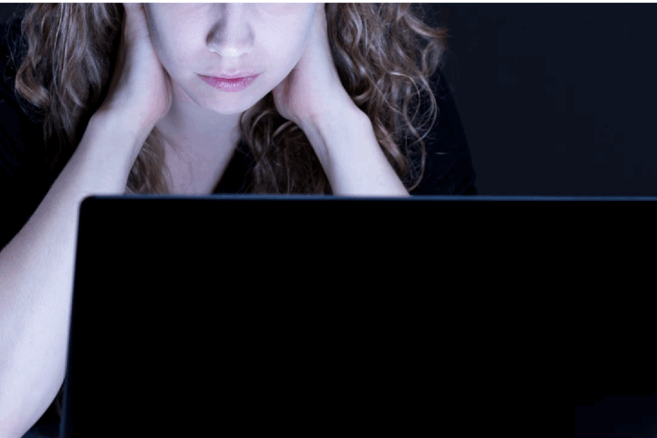 An image showing a woman using a laptop screen and looking worried or anxious.