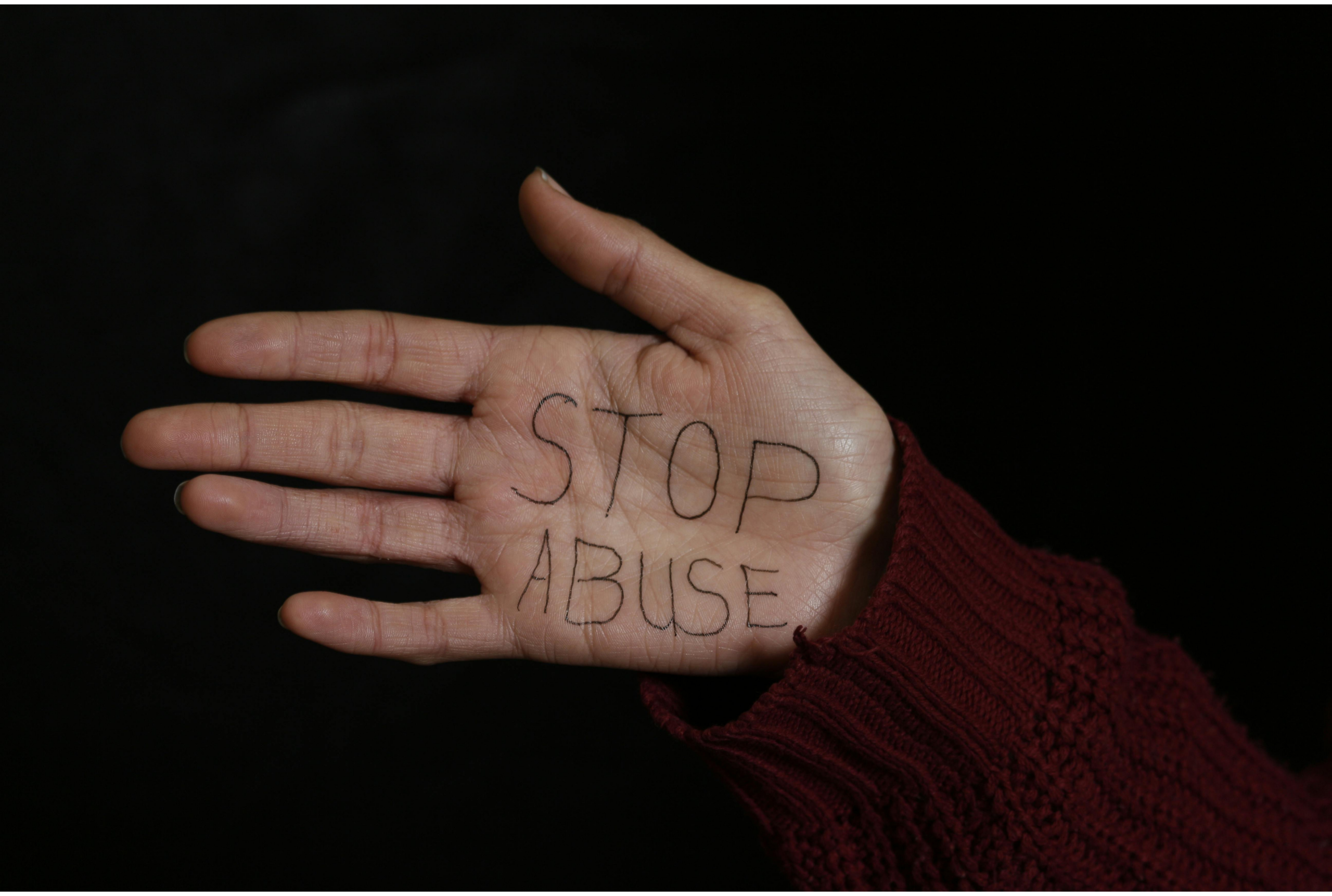 A photograph showing a hand with the writing 'Stop abuse' on it