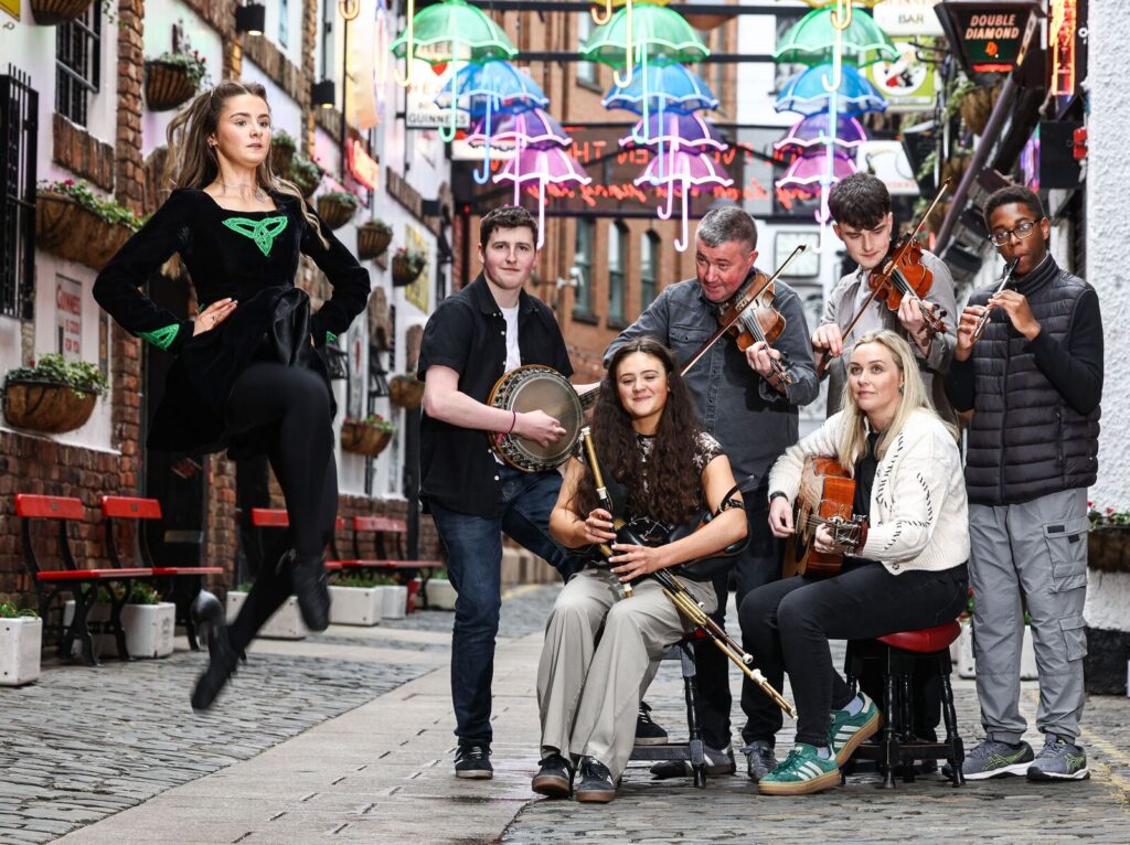 A photograph of six traditional musicians and an Irish dancer performing in a street in Belfast.